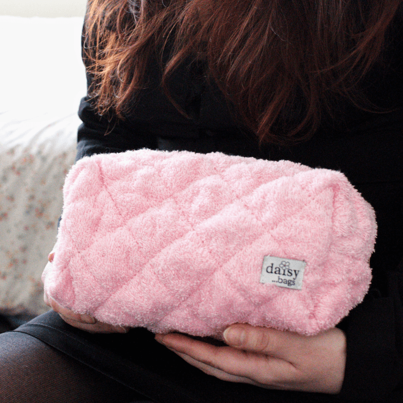 A young women holding the Leela pink makeup bag