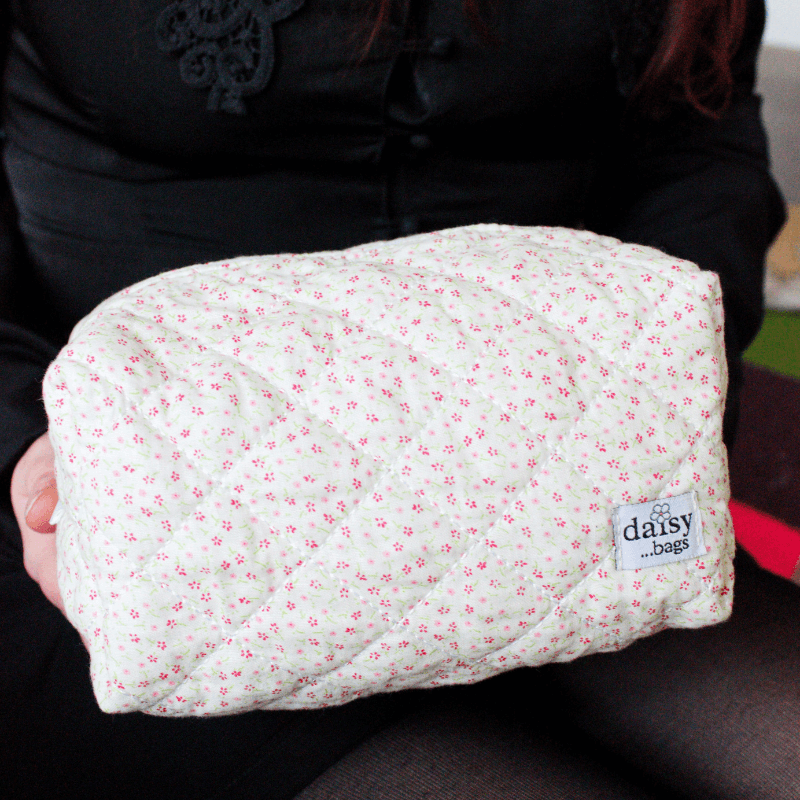 A young women holding the Bloom floral makeup bag